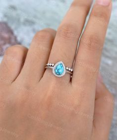 a woman's hand with a blue and white stone ring on her left hand