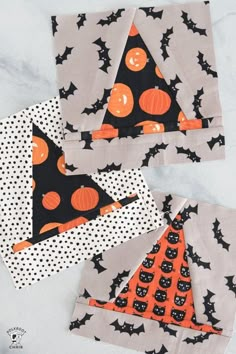 three pieces of fabric with black and orange pumpkins on them, one has a triangle