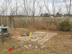 a picnic table made out of pallets in the middle of a field with tools on it