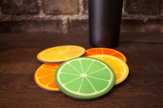 four slices of orange and lime sitting on top of a table next to a black cup