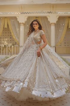 a woman in a white and gold bridal gown posing for the camera with her hands on her hips