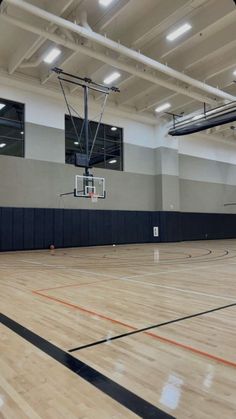 an indoor basketball court with hard wood flooring and lights on the side wall is empty