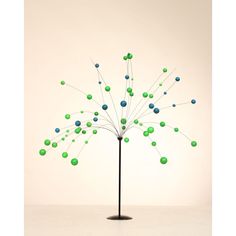 a tree with green and blue balls on it in front of a white wall or floor