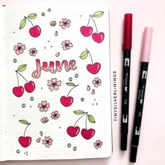 an open notebook with the word june written on it next to two markers and a pen