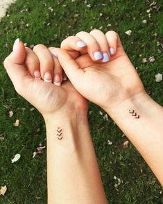 two hands holding each other with small tattoos on them