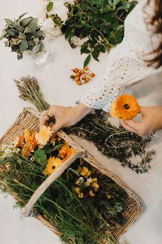 a woman is arranging flowers in baskets on a table with greenery and other plants