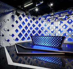 an empty stage with blue lights on the side and white squares on the wall behind it