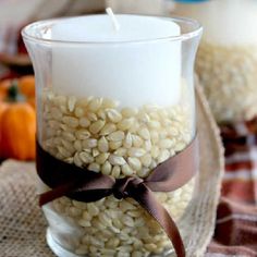 a candle is sitting in a glass container filled with grains