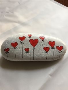 a rock with hearts painted on it sitting on top of a white sheet covered table