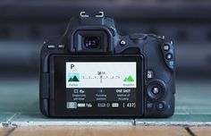 a digital camera sitting on top of a wooden table next to a wall and floor