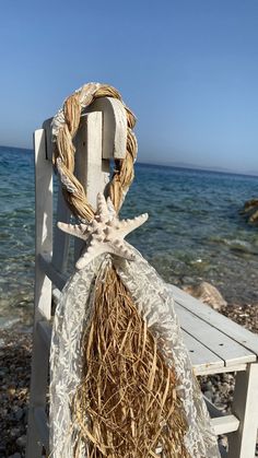 a white chair sitting on top of a sandy beach next to the ocean with a starfish hanging from it's rope