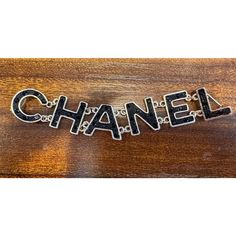 the word chanel written in metal letters on a wooden surface with chains hanging from it