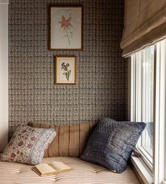 a window seat with pillows and a book on it