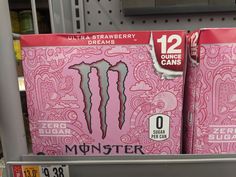 two boxes of monster energy drink are on display in a grocery store, one is pink and the other is red