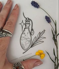 a person's hand with a ring on it next to some flowers and plants