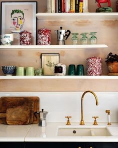 the shelves above the kitchen sink are filled with colorful vases and other decorative items