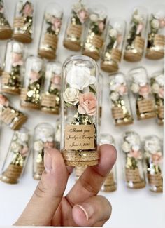 a person holding up a tiny bottle with flowers in it's corks on the side