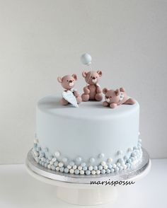 two teddy bears sitting on top of a white cake