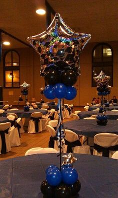 a room filled with tables covered in blue and white tablecloths, balloons and centerpieces