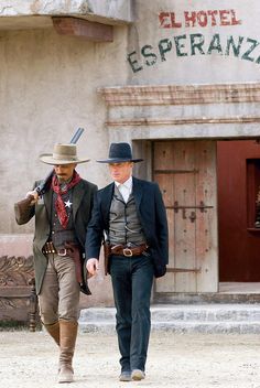 two men dressed in period clothing walking down the street