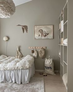 a white bed sitting in a bedroom next to a book shelf filled with stuffed animals