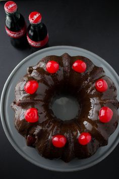 a chocolate bundt cake on a plate with two coke bottles