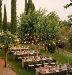 an outdoor dining area with tables and chairs set up in the grass, surrounded by trees