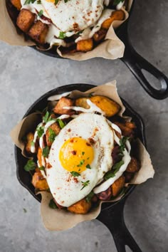 two cast iron skillets topped with fried eggs and hashbrowns next to each other