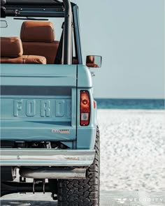 the back end of a blue truck parked on top of a beach