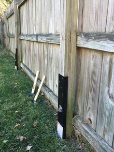 two baseball bats leaning against a wooden fence