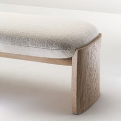 a wooden bench with a white upholstered seat and back rest on a plain surface