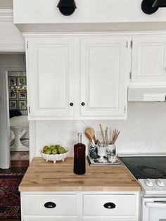 a kitchen with white cabinets and wooden counter tops