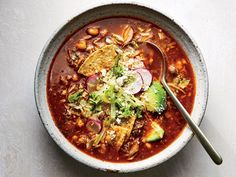 a bowl of chili soup with tortilla chips and avocado