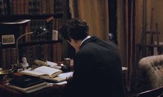 a man sitting at a desk in front of a bookshelf filled with books