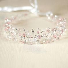 a tiara with pink and white flowers on it sitting on a table next to a glass vase