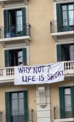 a banner that says why not? life is short hanging from the side of a building