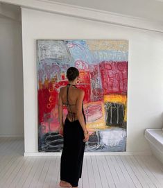 a woman standing in front of a painting on the wall with her back to the camera