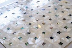 a white table topped with lots of different types of glass tiles on top of it