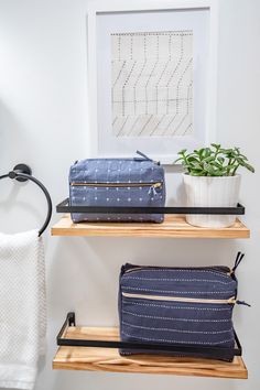 two bags are sitting on the shelves in this bathroom, one is blue and the other is white