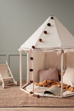 a white tent sitting on top of a wooden floor next to a bed with pillows