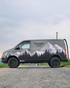 the van is parked on the side of the road with mountains painted on it's sides