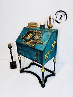 a small blue chest sitting on top of a table next to a clock and candles