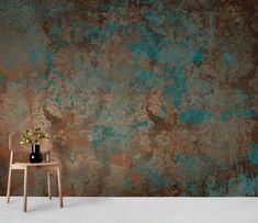 a wooden chair sitting in front of a wall with a vase on top of it