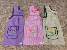 three aprons sitting on the floor next to each other, one with flowers in it