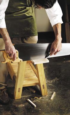 a man using a circular saw to cut planks on a piece of wooden furniture