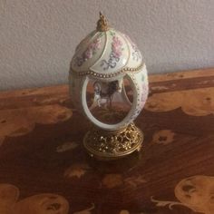 an ornate white and gold egg on top of a wooden table