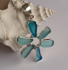 a blue and white flower pendant sitting on top of a shell