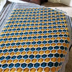 a crocheted blanket sitting on top of a carpet next to a dresser and bed