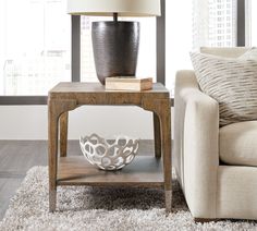 a living room with a couch, table and lamp on it in front of a window