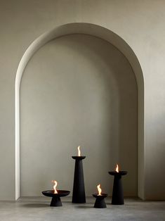 three black candles sitting in front of an arch